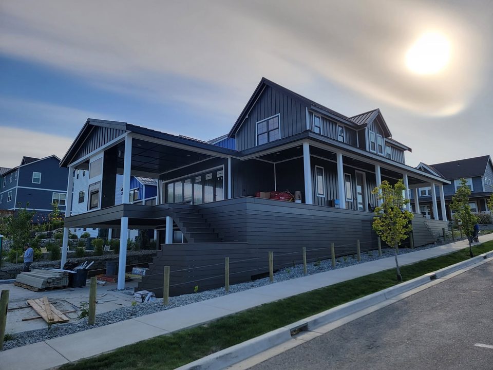 Dark blue house exterior with porch, pale trim and work materials visible.