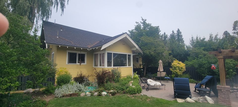 Rear view of a yellow house with windows and a garden.