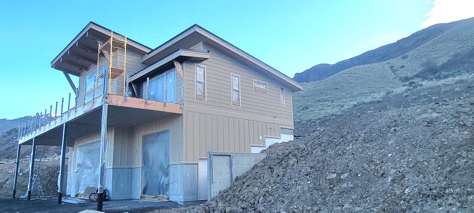 Hillside house exterior with work equipment visible.