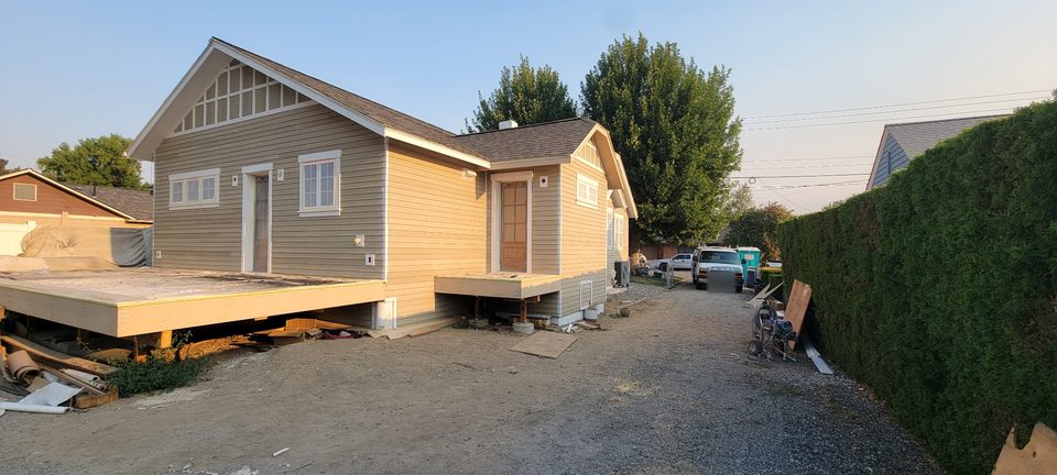 Small house exterior with yellow siding and a raised porch.